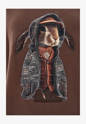 Brązowy sweter z wyhaftowanym królikiem w płaszczu i kapeluszu, ozdobiony teksturowanymi wzorami, muszką i brązowymi butami.