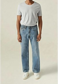 Jasnoniebieskie dżinsy o prostym kroju i pięciokieszeniowym designie, zestawione z jednolitą, jasnoszarą koszulką z okrągłym dekoltem oraz białymi butami.