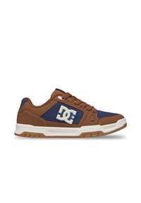 Χαμηλό sneaker σε καφέ και ναυτικό μπλε με λευκό λογότυπο DC στο πλάι και λευκή λαστιχένια σόλα, από το πλάι.
