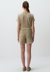 Beige Baumwoll-T-Shirt, das zu gestreiften Strickshorts in Beige und Creme passt. Die Shorts haben ein strukturiertes, wellenförmiges Muster und einen elastischen Bund.