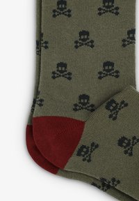 Calcetines verdes con un patrón de calaveras y huesos cruzados en negro, con talón y punta rojos, textura acanalada y diseño de longitud media.