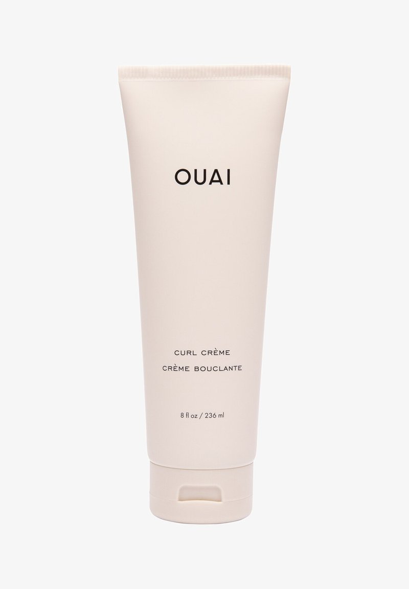 Crema per ricci OUAI in un morbido tubo beige, da 240 ml. Presenta un semplice testo nero con tappo a scatto, finitura opaca liscia e design minimalista.