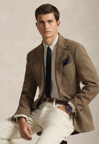 Καφέ σακάκι με σχέδιο ψαροκόκαλο πάνω από ριγέ πουκάμισο, σκούρη γραβάτα και κρεμ παντελόνι· διαθέτει μπλε τσεπάκι και ξύλινο ρολόι.