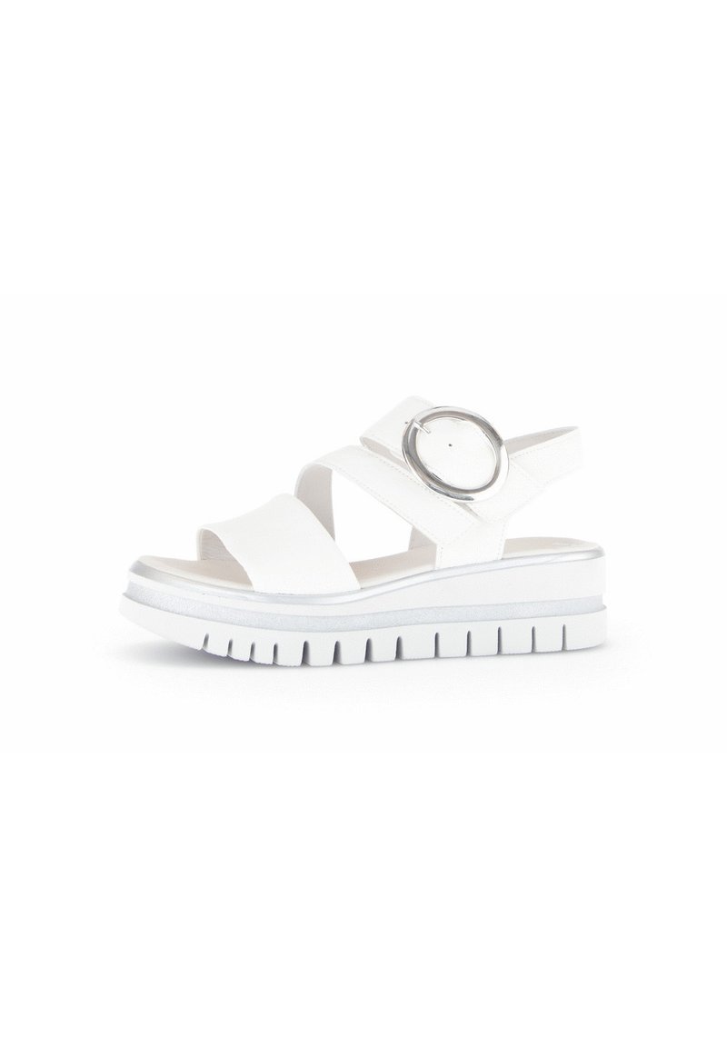White sandals with two wide cross straps and a circular silver accent, featuring a thick white sole with a ridged pattern.