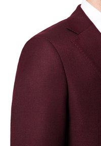 Burgundowy blazer o fakturze, dopasowany w talii, z klapami i subtelnymi detalami. Gładki materiał i wyraźny kształt.