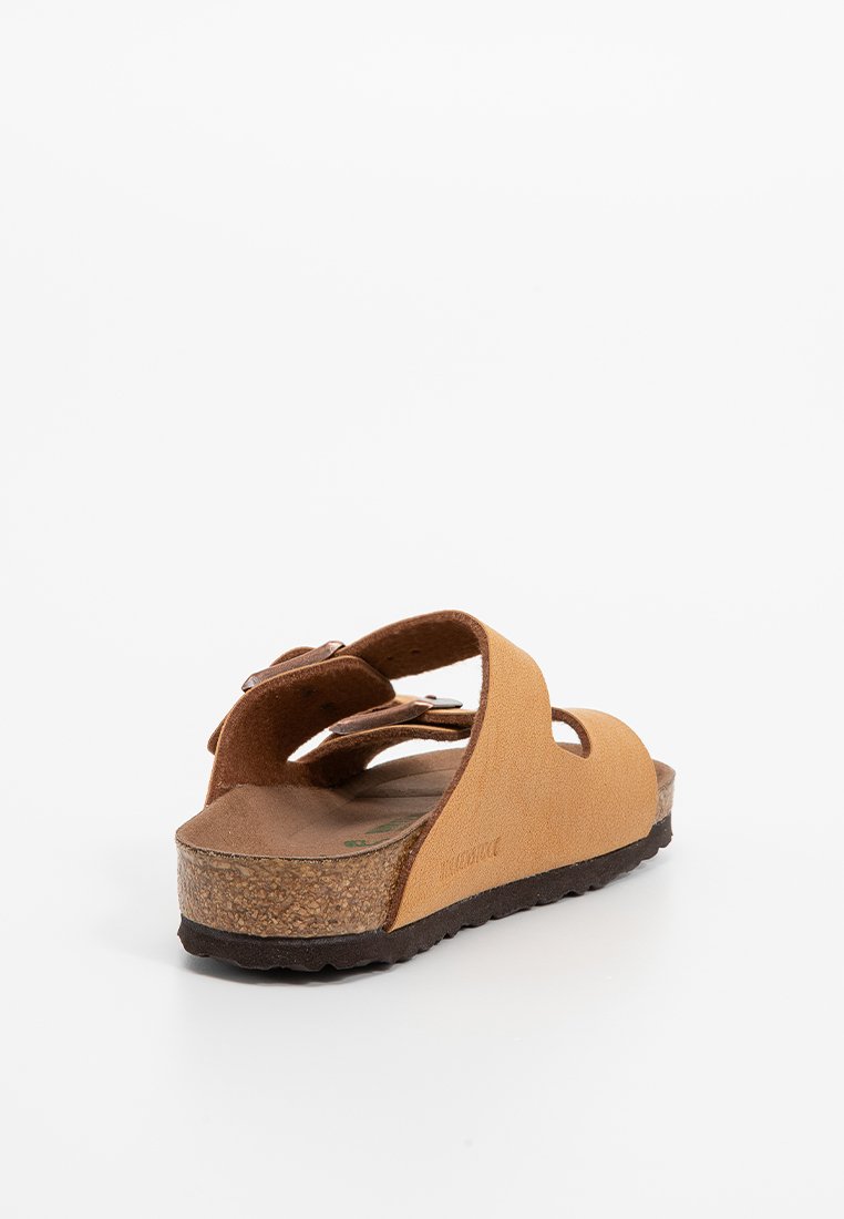 Sandale en suède beige avec semelle en liège, design découpé, deux sangles ajustables et semelle intérieure texturée. Dotée d'un talon bas pour le confort.