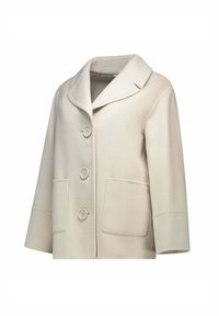 Cappotto color crema realizzato in tessuto morbido, con colletto sciallato, tre bottoni e due tasche frontali. Leggero con una vestibilità ampia.