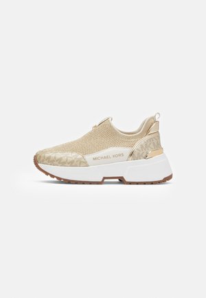 Baskets beige à enfiler avec empeigne en maille, semelle plateforme blanche, marque "Michael Kors" et détails à motifs sur l'avant et le talon.
