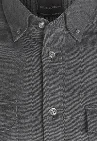 Camicia grigia con bottoni, in tessuto a spina di pesce, due tasche sul petto e bottoni argentati. L'etichetta riporta "Oscar Jacobson", taglia media.
