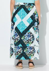 Gonna maxi con un design a patchwork e motivi floreali in blu, verde e nero. Realizzata in tessuto leggero con un orlo a balze.