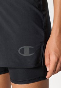 Čierne športové šortky z hladkého, elastického materiálu, s nenápadným šedým logom na dolnej ľavej strane. Čistý, minimalistický dizajn.