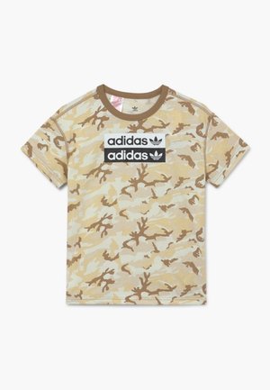 T-shirt à manches courtes beige et marron camouflage avec col marron et deux logos Adidas dans des rectangles noirs et blancs sur la poitrine.