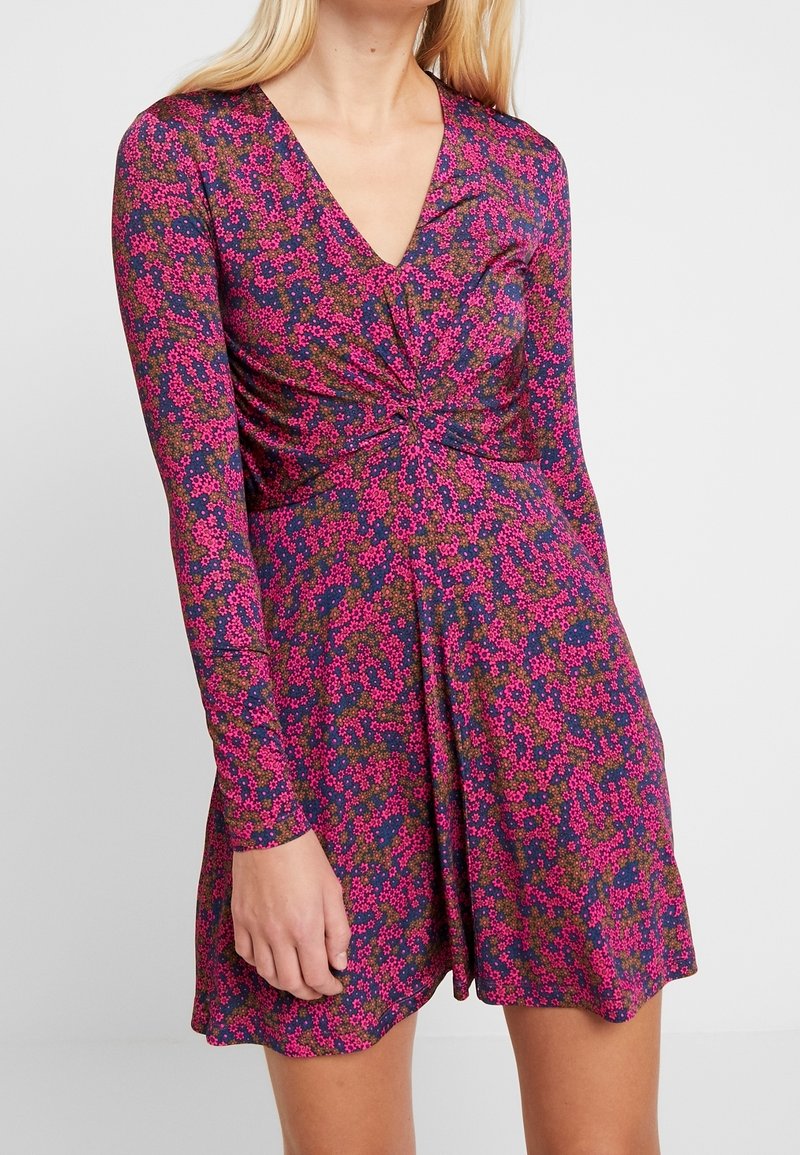 Sukienka z długim rękawem i dekoltem w kształcie V w różowo-granatowy kwiatowy wzór, z detalem w postaci związanej talii oraz zwiewnym dołem. Gładka tekstura materiału.