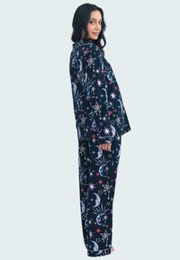 Marinblå pyjamas set med lång ärm och byxor; har stjärn- och månmönster i rosa, vitt och ljust blått. Mjuk tyg med en avslappnad passform.