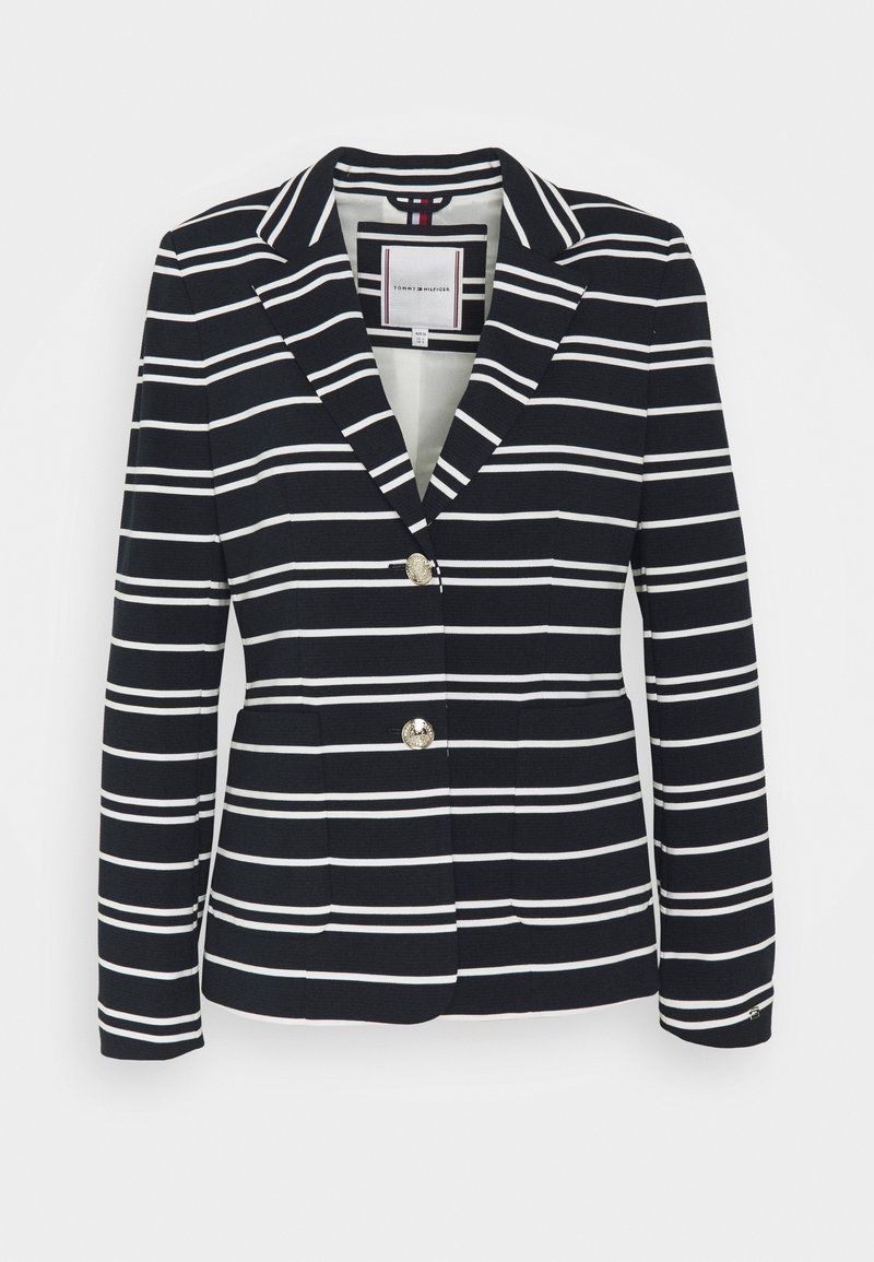 Granatowa marynarka w białe paski, z klapami w kształcie litery V, dwoma złotymi guzikami i kieszeniami z przodu. Teksturowany materiał z dopasowanym krojem.