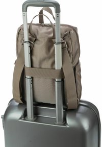 Maleta rígida gris con un mango retráctil y una mochila de tela marrón asegurada en la parte superior con correas ajustables.