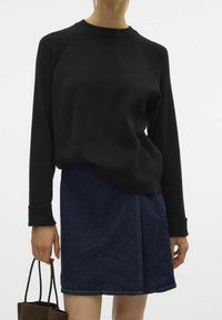 Czarny sweter z długim rękawem i raglanowymi rękawami, połączony z ciemnoniebieską dżinsową spódnicą. Stylizacja charakteryzuje się prostym wzornictwem i teksturowanym materiałem.