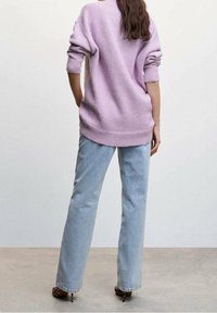 Pull lavender surdimensionné avec poignets et ourlet côtelés, associé à un jean bleu clair à jambes droites, mettant en valeur un design simple et décontracté.