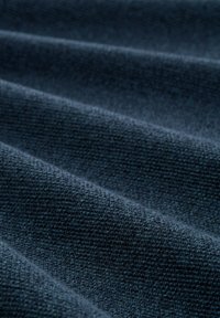 Wellige, dunkelmarinefarbene Stoff mit strukturierter Webart. Besitzt feine Rillen und eine weiche, matte Oberfläche, die dem Material eine subtile Tiefe verleiht.