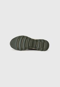 La semelle de chaussure présente un caoutchouc vert texturé avec des rainures prononcées et de légères ridges pour une meilleure traction ; design minimaliste avec un profil plat.