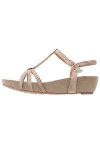 Sandale compensée en suede beige avec design à lanières T, bride de cheville ajustable, semelle plate, plusieurs lanières à l'avant et finition légèrement texturée.