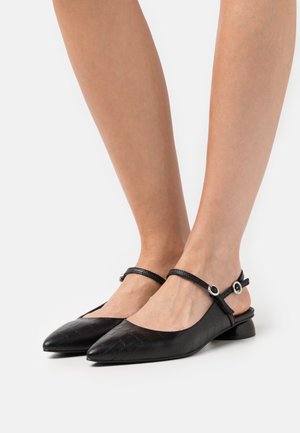 Chaussures slingback noires à bout pointu, fabriquées en matériau texturé présentant un motif crocodile. Bride ajustable avec quincaillerie en argent.