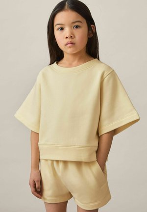 Lys gul bomuldsblandings sweatshirt med brede ærmer og rund hals, parret med matchende shorts, der har en afslappet pasform og struktureret stof.
