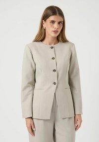 Lys grå blazer med rund halsudskæring, fem knaplukninger, struktureret design og to frontlommer med subtile syning detaljer.
