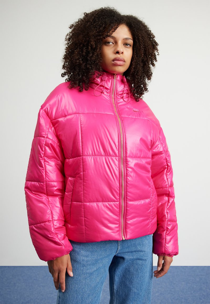 Helle pinke Puffjacke mit hohem Kragen, Reißverschluss vorne und gestepptem Design. Mit elastischen Bündchen und einer glatten, glänzenden Textur.