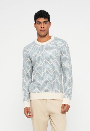 Light blue and white chevron-patterned knit sweater with a round neckline and ribbed cuffs and hem, made of soft, textured material.