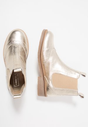 Paire de bottines Chelsea en cuir doré métallique avec panneaux latéraux élastiques beige et semelles en caoutchouc marron clair sur fond blanc.