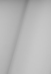 Biała tkanina o gładkiej, matowej teksturze, z delikatnym wzorem splotu i lekkim połyskiem, układająca się w fałdy i nakładająca na siebie.