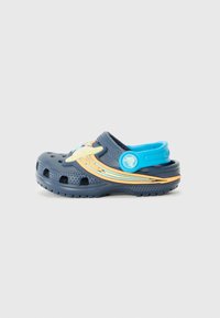 Blå crocs med en ventilerande design, som har orange och gula detaljer, cirkulära utskärningar för ventilation och en justerbar hälrem.