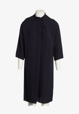 Longue robe noire à manches trois-quarts, col montant et détail lacé, présentée sur un mannequin blanc.