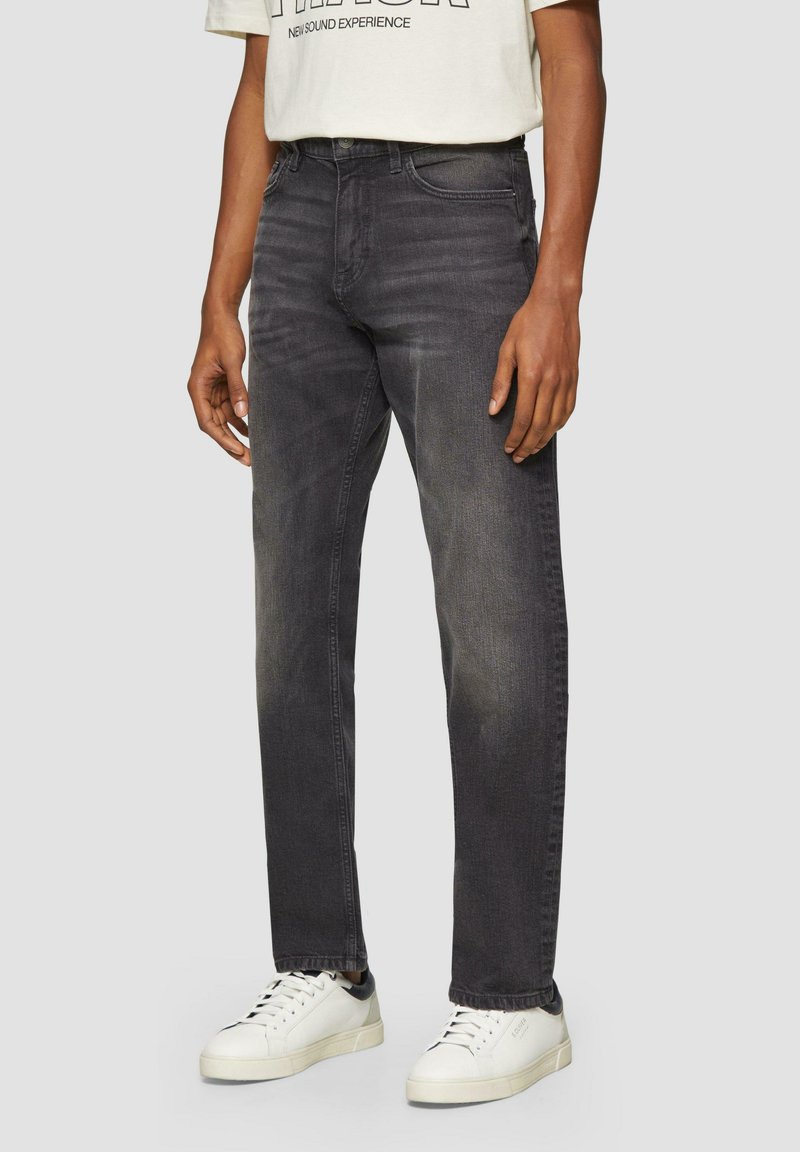 Czarne dżinsy o prostym kroju, z delikatnym wyblaknięciem i pięcioma kieszeniami, zestawione z białymi trampkami.