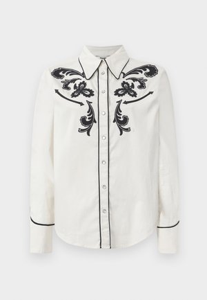 Witte katoenen blouse met zwarte bloemenborduursels op de borst, zwarte bies langs de kraag en manchetten, en een knoopsluiting aan de voorkant.