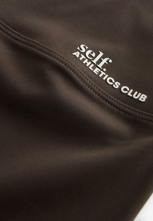 Zwarte atletische stof met een gladde textuur, met witte tekst: "self ATHLETICS CLUB" op de zijnnaad en subtiele stiksel details.