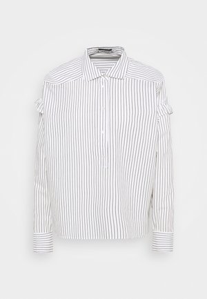 Chemise blanche à manches longues avec fines rayures verticales noires, patte de boutonnage partielle, col, et petits nœuds en tissu sur les parties supérieures des manches.