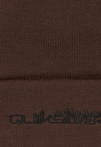 Bruin gebreid stof met een geribde textuur en een zwart Quiksilver-logo, waarin een naadloos ontwerp wordt benadrukt zonder zichtbare naden.