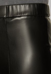 Black leather skirt with a smooth texture, wide waistband, and visible stitching along the sides, showcasing a fitted design.