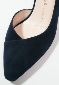 Chaussure à talon haut en daim bleu marine avec un bout pointu et un design à découpes. Texture lisse et douce avec une doublure intérieure beige clair.