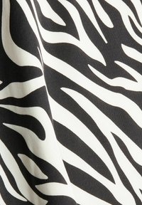Zwart-witte stof met een zebra-strepenpatroon, met een gladde textuur en golvende lijnen die scherp contrasteren met de achtergrond.