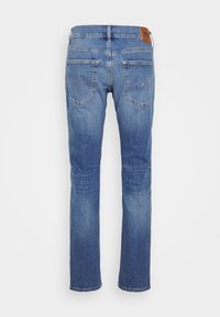 Blå denimjeans med rak benstil, fem fickor och en brun läderetikett på midjan. Lätt färgblekning och strukturerad tyg.