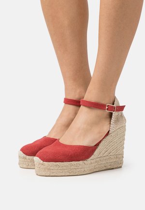 Chaussures compensées en tissu rouge avec une semelle en jute et une bride de cheville, présentant un bout arrondi et un accent de talon beige texturé.