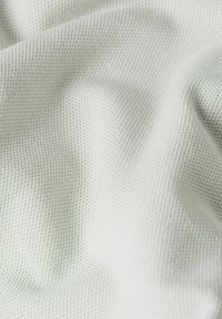 Tela texturizada de color verde claro con un patrón de gofre, que muestra un acabado suave y un ligero brillo, dispuesta para resaltar pliegues y contornos suaves.