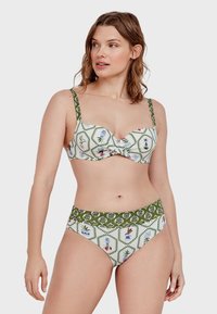 Bikini blanco con flores y detalles verdes. La parte de arriba presenta un diseño estructurado y tirantes ajustables; la parte de abajo tiene un corte de cintura alta con una banda estampada.