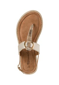 Beige flip-flop sandal med ett metalliskt guldrem och en cirkulär detalj, med en texturerad brun fotbädd och glittrig guldkant.