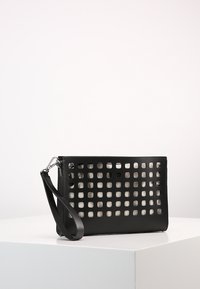 Černá kožená kabelka do ruky s čtvercovým vykrojeným vzorem, zápěstním páskem a elegantním designem s hladkou texturou.