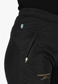 Black athletic pants with a zippered pocket, featuring a small blue and yellow Swedish flag patch and gold "SWEDEMOUNT" logo detail.
