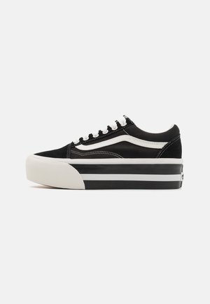 Niskie czarno-białe sneakersy z grubą podeszwą, białymi sznurowadłami i białym paskiem wzdłuż boku na jednolitym tle.